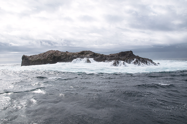 ocean splashing against a broad rock island
